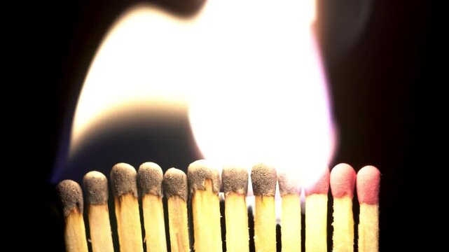 Many matches are lit and burn with fire on a black background, the fire is burning