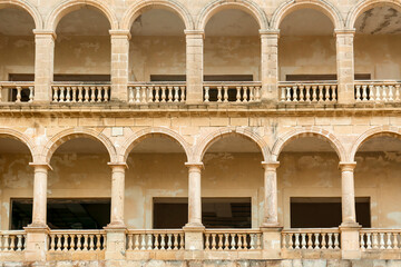 Naklejka premium Historic stone archways and balustrades of an abandoned building facade, architectural detail and decay, the weathered stone columns and arches show signs of decay and neglect