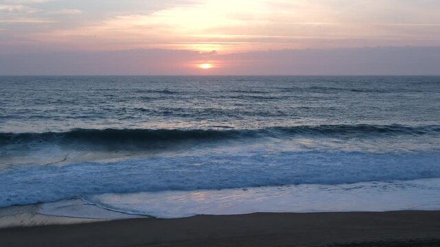 Static shot of calm ocean waves breaking on the sandy beach at sunset, Labenne-Ocean, Landes, France