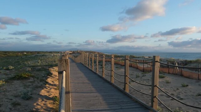 Static shot of a wooden walkway leading to the beach at Labenne-Ocean with the Pyrenees mountains in the distance, Landes, France