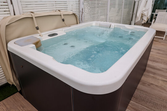 Outdoor hot tub with bubbling water and beige cover on a wooden deck for relaxation and wellness, the spa offers relaxation and wellness, providing a luxurious leisure experience