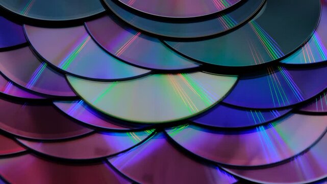 Reflection of the surface of a DVD discs, multiple optical discs stacked on top of each other like fish scales, colorful lines on the surface are caused by thin-film interference and diffraction
