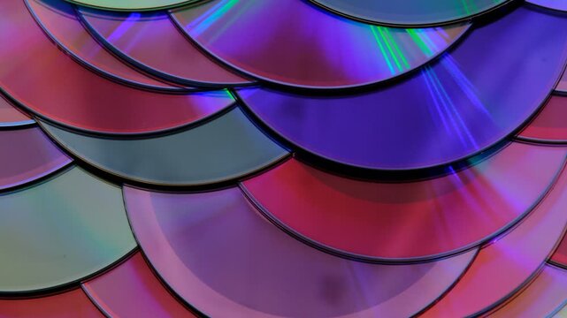 Reflection of the surface of a DVD discs, multiple optical discs stacked on top of each other like fish scales, colorful lines on the surface are caused by thin-film interference and diffraction