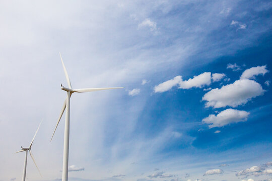 Two wind turbines against a partly cloudy sky