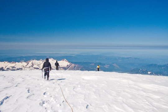 Roped mountaineering team on a snowy summit ridge