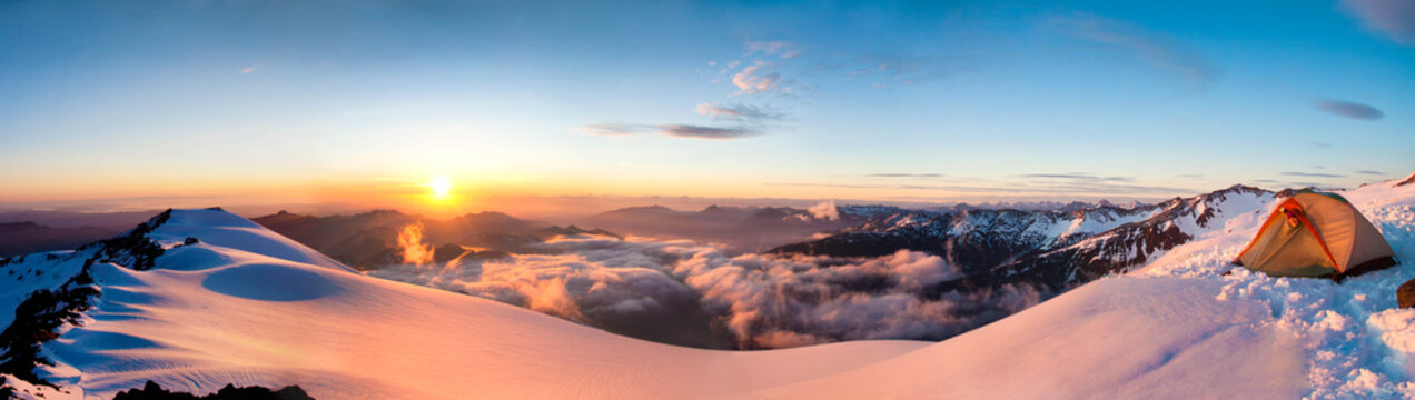 Panoramic view of woman in tent on mountain ridge at sunset