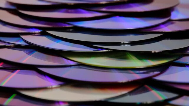 Reflection of the surface of a DVD discs, multiple optical discs stacked on top of each other like fish scales, colorful lines on the surface are caused by thin-film interference and diffraction