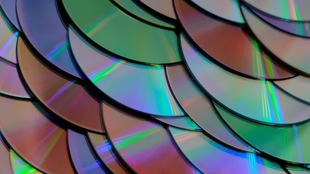 Reflection of the surface of a DVD discs, multiple optical discs stacked on top of each other like fish scales, colorful lines on the surface are caused by thin-film interference and diffraction