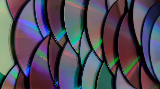 Reflection of the surface of a DVD discs, multiple optical discs stacked on top of each other like fish scales, colorful lines on the surface are caused by thin-film interference and diffraction