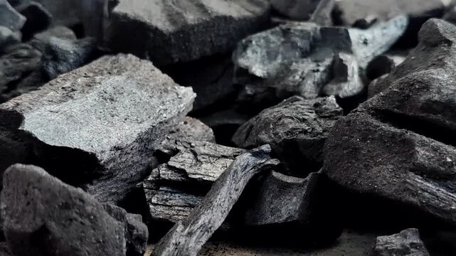 A collection of charcoal. Charcoal is a black, carbonaceous residue produced by burning wood without oxygen (pyrolysis). This material is widely used as a cooking fuel