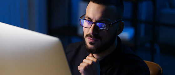 Obraz premium Male trader with eyeglasses working in office at night