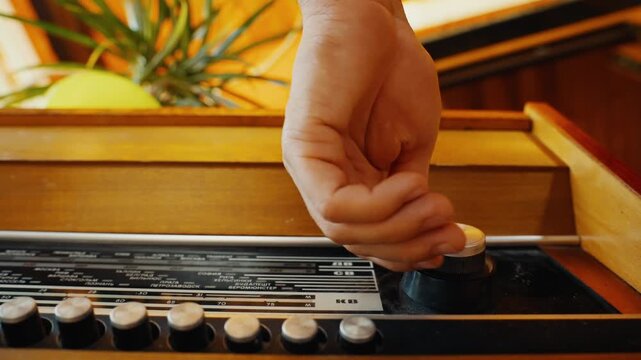 Person's hand adjusting knobs on a vintage radio