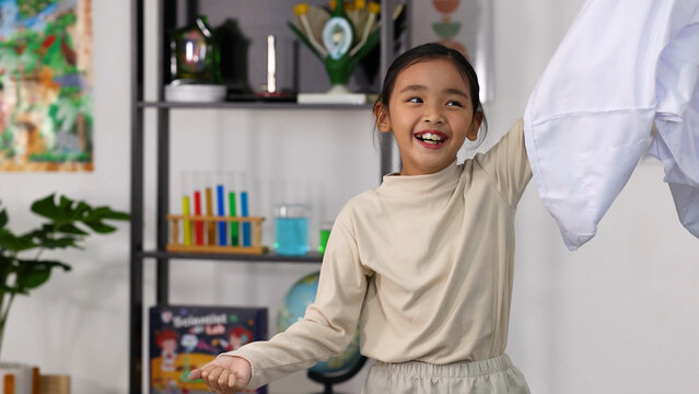 Cheerful Asian Schoolgirl Laughing and Playing with a White Lab Coat