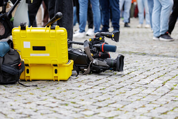 Fototapeta premium Professional Video Camera and Yellow Equipment Case on Cobblestone Street