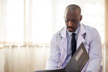 Naklejka premium Doctor in a white coat reviewing documents in a bright office.