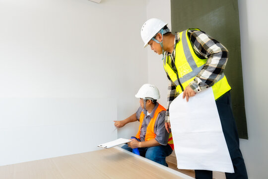 Engineers' Meticulous Detail Check for Room Quality:Engineers precisely inspecting the lower wall and baseboard areas in a new room,ensuring comprehensive quality assurance from top to bottom.