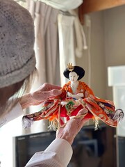 Naklejka premium 雛人形を持つ高齢女性_縦