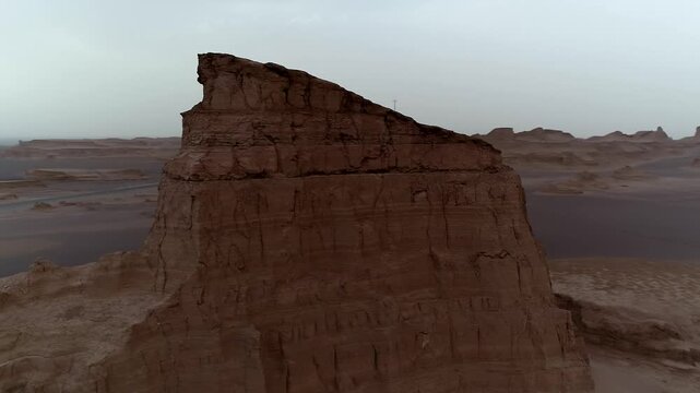 Tall yardang tower dominates hazy desert landscape with wind erosion creating powerful natural rock scene ideal for geology and landscape stock video content.