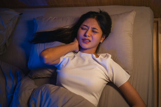 Waking up with a headache has problem with structural posture She had neck and shoulder pain. Beautiful woman can't sleep moving restless on bed. Young woman having bad dream