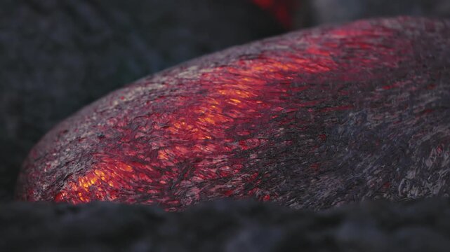 Extreme macro close-up of incandescent lava expanding and slowly advancing across the surface of Kīlauea Volcano in Hawaii. The glowing molten rock displays intricate textures and vivid red-orange pat