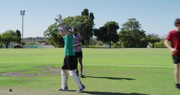male teammates effecting run-out at stumps, celebrating on pitch