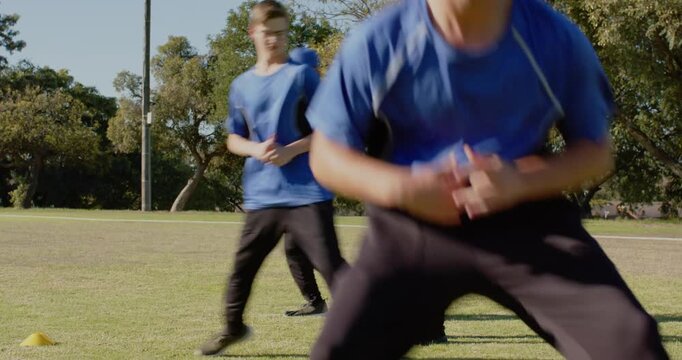 Diverse baseball team listening to teenage male coach on baseball field, with caps, foul line