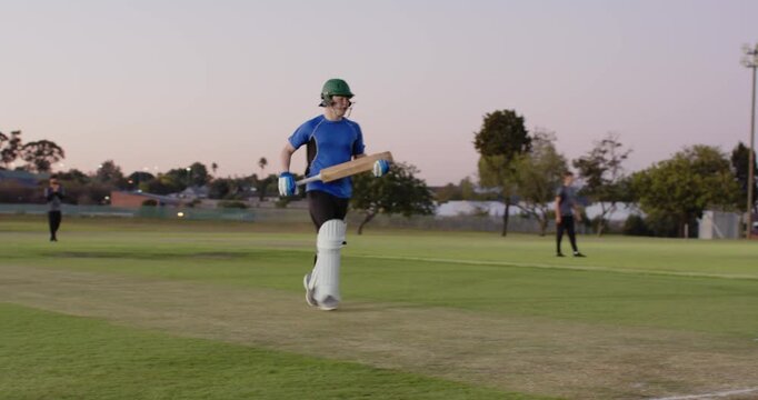Male batsman reacting to delivery on pitch, driving bat, sprinting to crease to score run