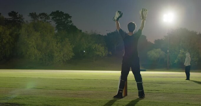 Striker sprinting to far end post-shot partner appealing run-out on field under floodlights