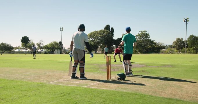 Male bowler bowling to batsman swinging bat to hit, missing wicketkeeper and collecting ball