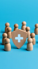 Obraz premium Wooden figurines representing healthcare and insurance concepts with a shield symbolizing protection, isolated on a vibrant blue background.