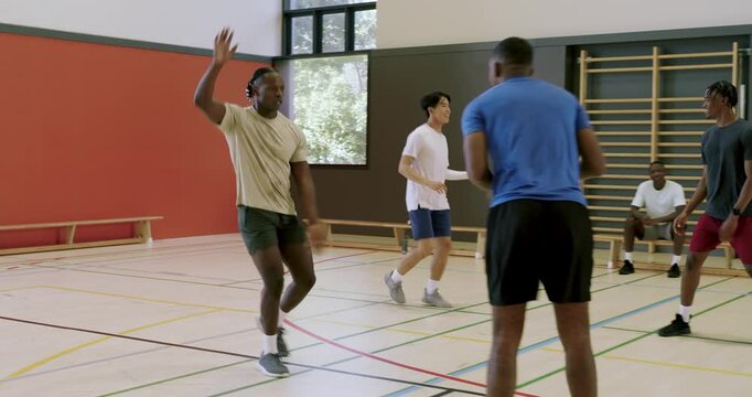 After fist bumps diverse male team stealing ball driving for score at gym jogging back