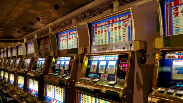 A captivating close up dolly shot of a row of illuminated slot machines in a vibrant casino.