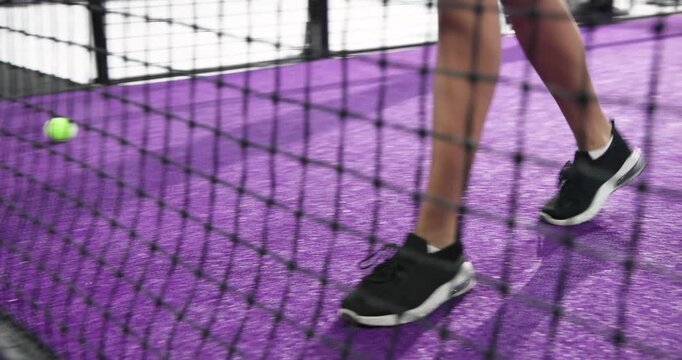 Indian woman athlete noticing padel racket swinging from net, reaching, posing at padel court
