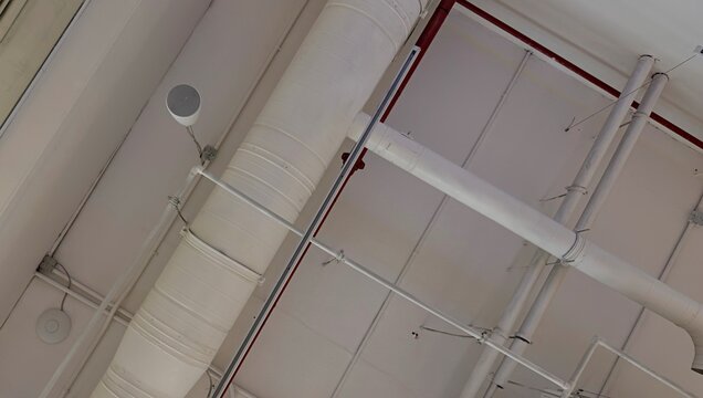 Industrial ceiling background with white ventilation ducts and pipes