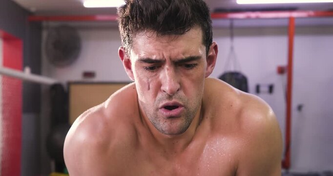 Adult male boxer reacting to mouth guard pain spitting out rubbing with gloves bracing in ring