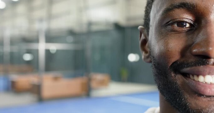 African american man receiving fixed shot, smiling from neutral to full smille on court, copy space