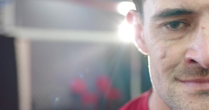 Mid-adult man in red shirt blinking and smiling when light flare hits mesh partition