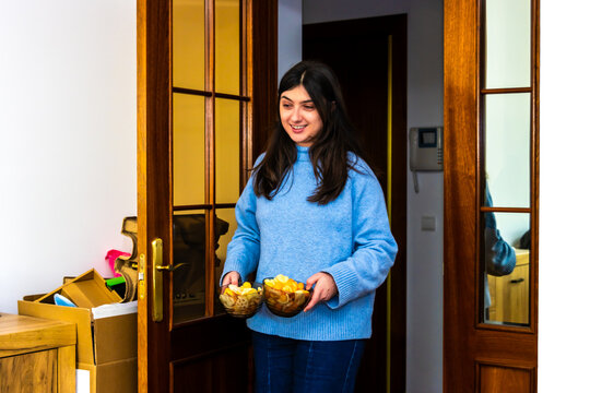 Woman holding bowls of snacks, preparing for special event, hosting friends at home