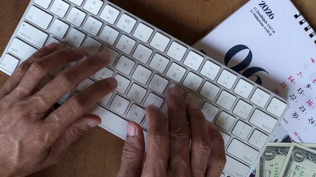 Close up diagonal or tilted top down shot of hand finger Asian male typing on modern computer wireless keyboard
