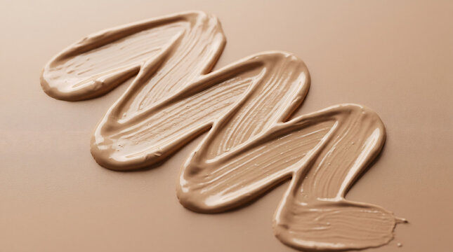 Creamy liquid makeup foundation stroke texture swiped on a smooth beige skin tone background