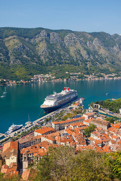 Aerial view of large cruise ship docked at the historic port of Kotor old town, beautiful bay and mountains landscape, authentic travel destination in Montenegro