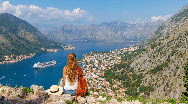Young female traveler with backpack enjoying the panoramic view of the Bay of Kotor, authentic travel, adventure and freedom concept in Montenegro