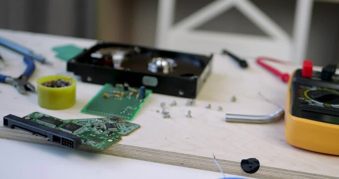 Electronics repair workspace with multimeter, tools and computer components on workbench. Technical setup highlights diagnostics, maintenance and hands-on engineering activities.