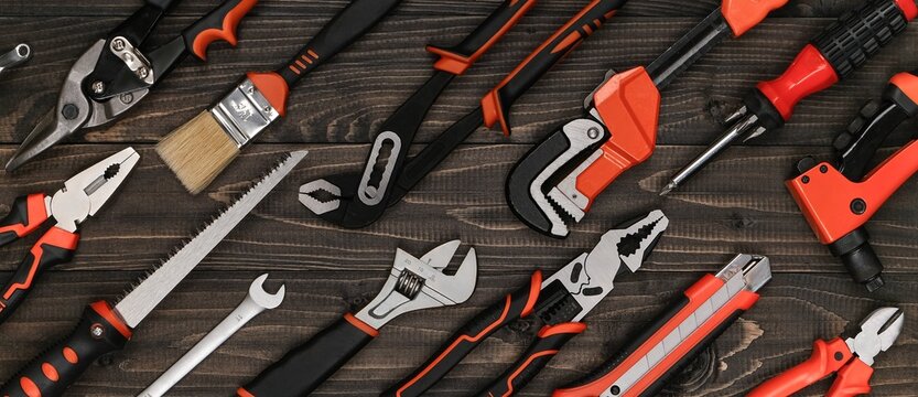 High-angle view of an organized hand tool assortment on a dark wood workshop bench. Professional rustic industrial design layout for hardware store branding and web banners.