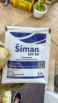 Close up of a Siman 200 SG insecticide sachet held by a gloved hand in a sunlit garden ideal for product catalog, gardening tutorial, safety editorial, 5 May 2026 Subitica, Serbia