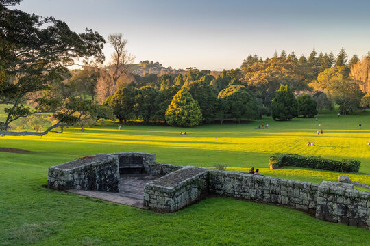 A couple enjoys a peaceful afternoon in Cornwall Park, Auckland, New Zealand . People relax on the grass as the sun casts long shadows.