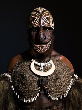 A tribesman wearing a Papua New Guinea Sepik River painted spirit mask with geometric tattoo patterns