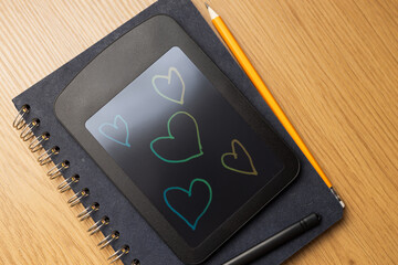 Black lcd writing tablet with multicolor heart sketches on screen for romantic notes and stationery background or greeting card design © Andrii Zastrozhnov