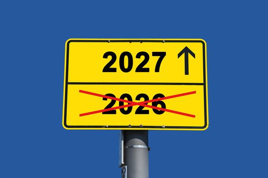 Yellow Road Sign Indicating the New Year 2027 with a Forward Arrow over a Crossed Out Year 2026 against a Clear Blue Sky