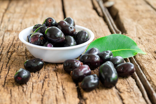 Close-up of 'Indian blackberry' or Jamun (Syzygium cumini) fresh fruits, on a wooden background.